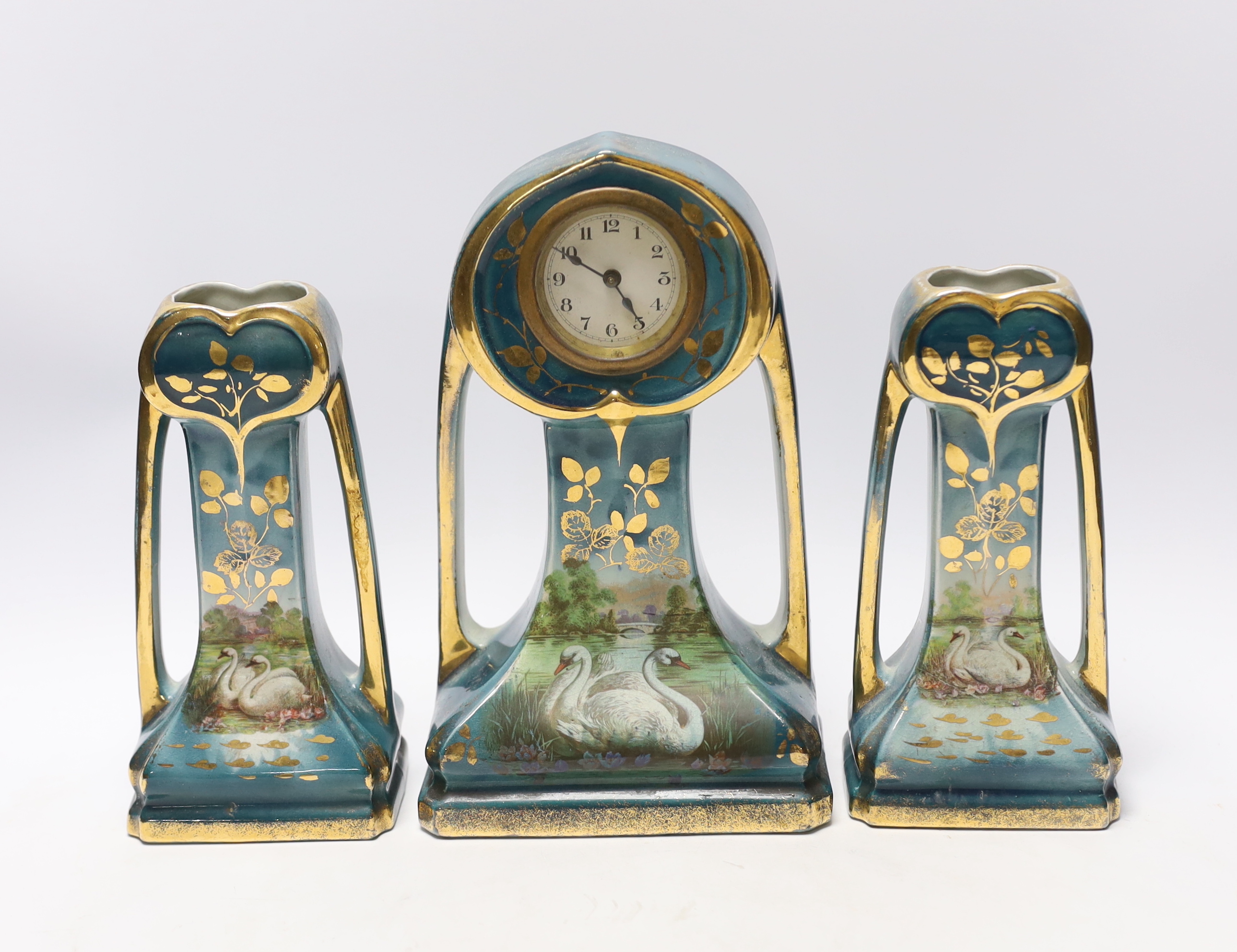 An Art Nouveau clock garniture, decorated with swans in a landscape, stamped ‘Made in England’ to the reverse, clock 23.5cm